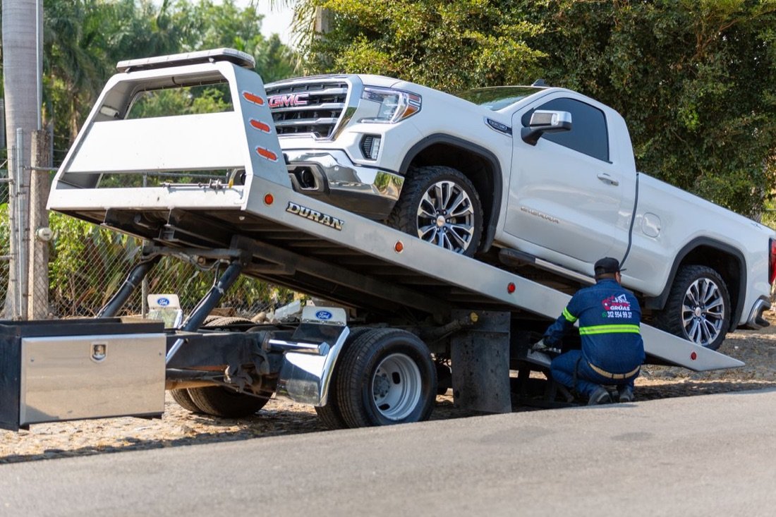 A flatbed rollback tow truck loading a pickup